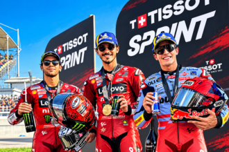Ilustrasi AI tiga pembalap MotoGP berpose di podium Tissot Sprint dengan seragam balap dan helm.